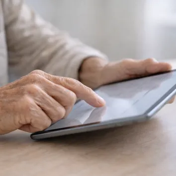 Imaxe dunha tablet e unhas mans tocando a mesma